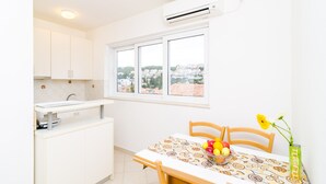 A kitchen with a window, a table with a fruit bowl, and a vase with flowers. - A4-harmony Apartment Close To The Sunset Beach And Lapad Promenade (Dubrovnik)