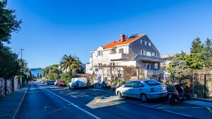 A street with parked cars and a building with a red roof. - A4-harmony Apartment Close To The Sunset Beach And Lapad Promenade (Dubrovnik)