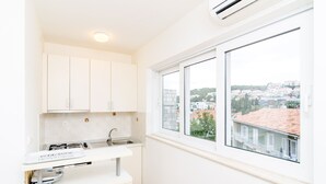 A modern kitchen with white cabinets, a sink, and a window overlooking a cityscape. - A4-harmony Apartment Close To The Sunset Beach And Lapad Promenade (Dubrovnik)