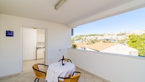 A balcony with a table and chairs, a view of a town, and a sign indicating a studio apartment. - A4-harmony Apartment Close To The Sunset Beach And Lapad Promenade (Dubrovnik)