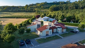 A modern two-story house with a red-tiled roof, surrounded by lush greenery and a hilly landscape. - Room in Guest Room - Spacious Double Room in Alba (Alba)
