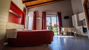 A bedroom with a bed, a wooden ceiling, a window with curtains, and a view of the outside. - Room in Guest Room - Spacious Double Room in Alba (Alba)