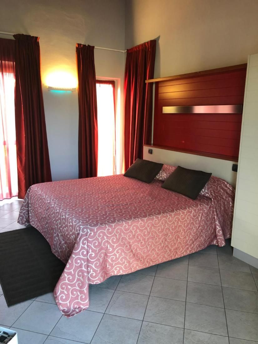 Ein Schlafzimmer mit Bett, Vorhängen, Kopfstütze und Fenster.