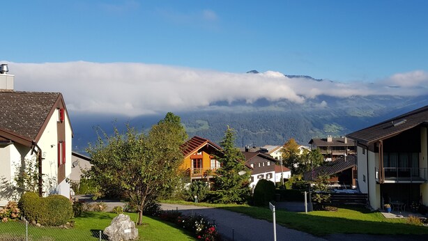 A residential area with houses, a paved road, and a mountain backdrop. - Elfe - Apartments Apartment for 6 Guests With Patio (Emmetten)