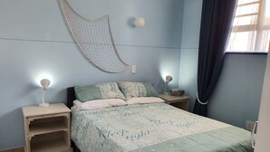 Une chambre à coucher avec un lit, deux tables de chevet, un fauteuil suspendu et une fenêtre avec des rideaux.