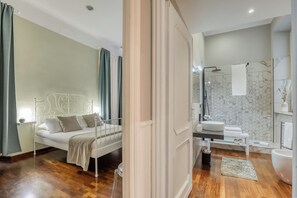 A modern bedroom with a bed, bedside table, and a bathroom with a sink, mirror, and bathtub.
