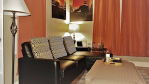 A living room with a sofa, two lamps, a coffee table, and a curtain. - The Bungalow at Grand Forks (Grand Forks)