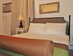 A neatly made bed with white linens, a bedside lamp, and a mirror on the wall. - Arhaus 2 - Riverside Park (Grand Forks)