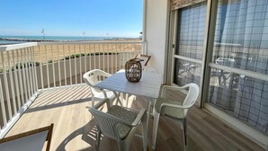 A balcony with a table and chairs, overlooking a beach. - Stunning Seafront Apartment (Caorle)