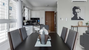A modern dining area with a black table, grey upholstered chairs, and a decorative basket centerpiece. - Luxurious Apartment In The Heart Of Santo Domingo (Santo Domingo)