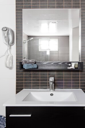 A modern bathroom with a white sink, a mirror, and a hairdryer mounted on the wall. - Luxurious Apartment In The Heart Of Santo Domingo (Santo Domingo)