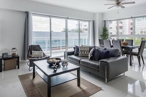 A modern living room with a sofa, coffee table, and dining area. - Luxurious Apartment In The Heart Of Santo Domingo (Santo Domingo)