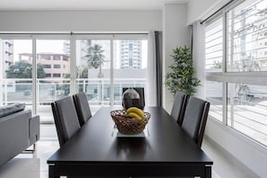 A modern dining area with a dark wooden table, grey upholstered chairs, and a woven fruit basket on the table. - Luxurious Apartment In The Heart Of Santo Domingo (Santo Domingo)
