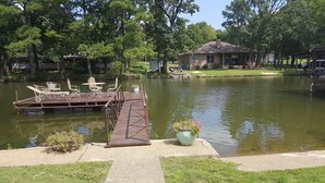 A lakeside dock with chairs and a table, surrounded by greenery and a house in the background. - Waterfront Listing - 3 Bedroom 3 Bath on Secluded Private Cove,great Location (Hot Springs)