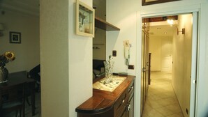 A hallway with a door leading to a room, a vase with flowers on a table, and a framed picture on the wall. - Roma Chic House - Luxury Apartment 1 People for Business Studio (Rome)