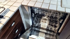 An open dishwasher with a label, a coffee maker, and a container labeled "THE" on a tiled kitchen counter. - Roma Chic House - Luxury Apartment 1 People for Business Studio (Rome)