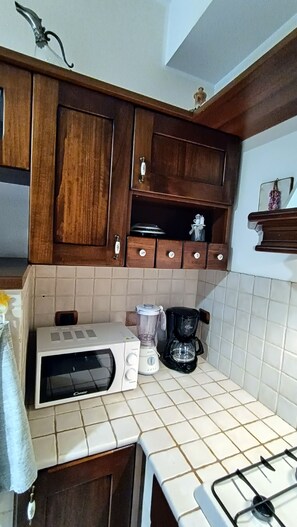 A kitchen with wooden cabinets, a microwave, a blender, and a coffee maker. - Roma Chic House - Luxury Apartment 1 People for Business Studio (Rome)