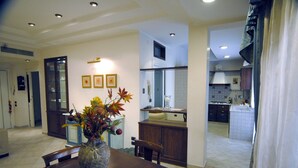 A dining area with a table, chairs, and a vase of flowers. There is a kitchen visible in the background with cabinets and appliances. - Roma Chic House - Delightful Luxury Apartment 3 People, With Jacuzzi (Rome)