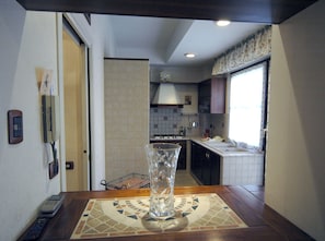 Une cuisine avec un mur recouvert de carreaux, une cuisinière et une fenêtre avec des rideaux.