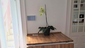 Ein kleiner Küchenbereich mit einer Holzinsel, zwei Barhocker, einer Topforchidee und einer Wandleuchte.