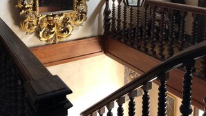 Una escalera con barandales ornamentados y un espejo grande y decorativo.
