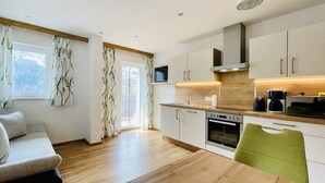 Een moderne keuken met houten kastjes, een ingebouwde oven en een eethoek met een groene stoel.