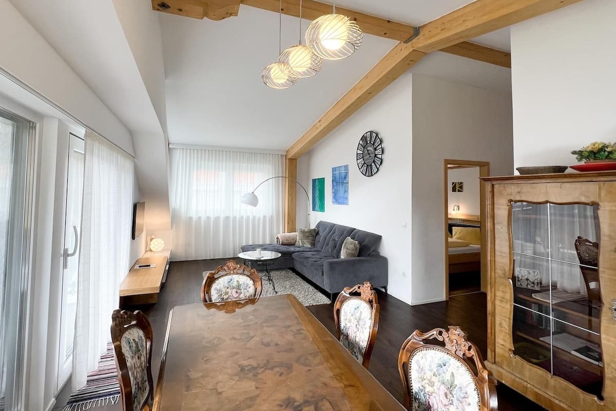 A dining area with a wooden table and chairs, a sofa, and a decorative cabinet.