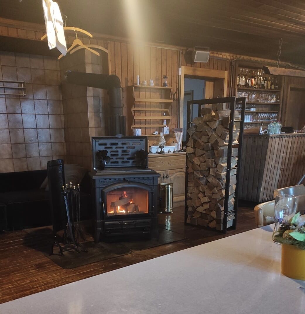 A cozy room with a wood-burning stove, wooden shelves, and a bar area.