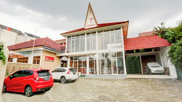 A building with a prominent 'TOBANA' sign, a covered parking area, and a red car parked in front. - Capital O 90066 Tobana Pejaten House (Jakarta)