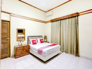 A neatly arranged bedroom with a bed, bedside table, and a mirror. - Capital O 90066 Tobana Pejaten House (Jakarta)