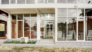 A modern building with large glass windows, a brick facade, and outdoor seating visible through the windows. - Capital O 90066 Tobana Pejaten House (Jakarta)