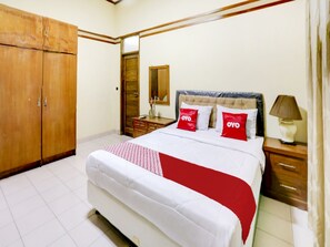 Un dormitorio con una cama grande, un armario de madera, una mesita de noche, una lámpara y un espejo.