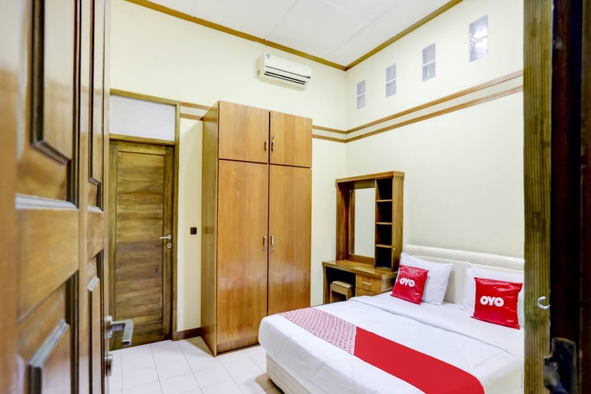 Ein Schlafzimmer mit Bett, einem Holzschrank, einem Spiegel und einem Schreibtisch.
