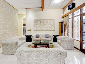 A living room with patterned sofas, a coffee table, and a decorative wall piece. - Capital O 90066 Tobana Pejaten House (Jakarta)