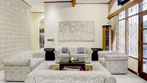 A living room with patterned sofas, a coffee table, and a decorative wall piece. - Capital O 90066 Tobana Pejaten House (Jakarta)