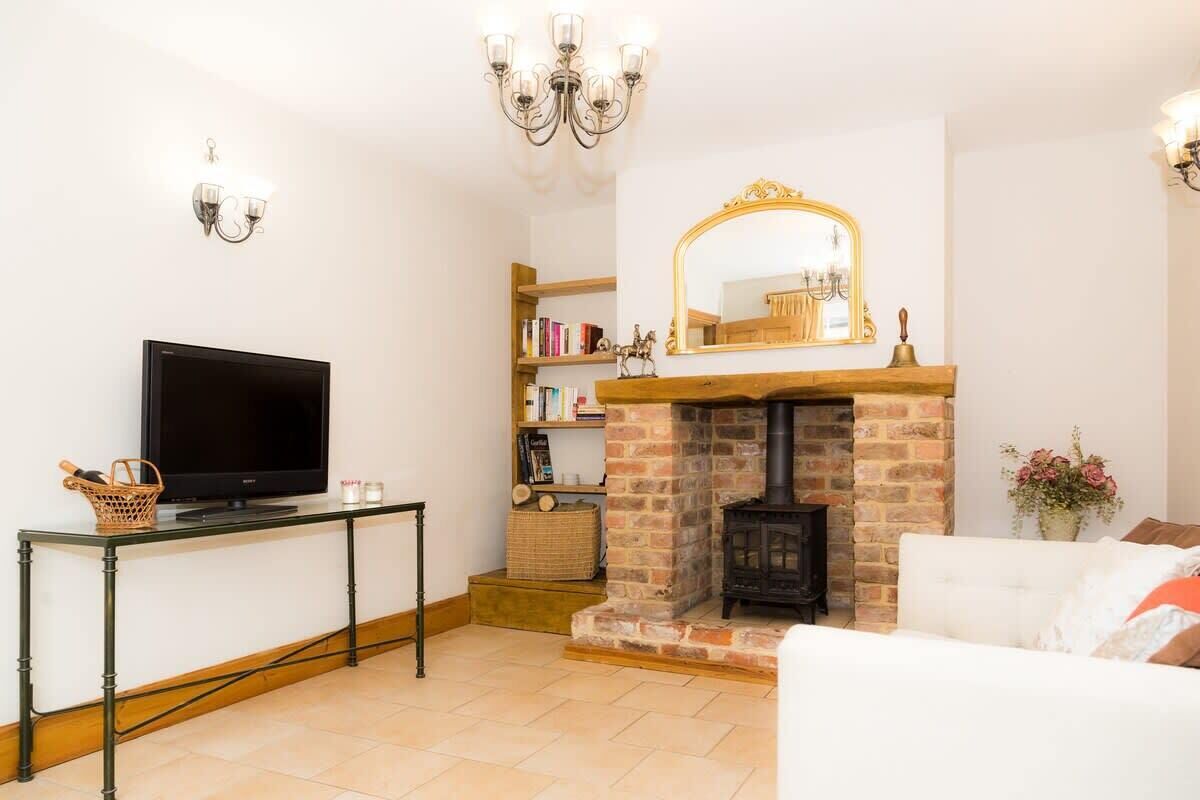A living room with a fireplace, a television on a table, and a bookshelf.