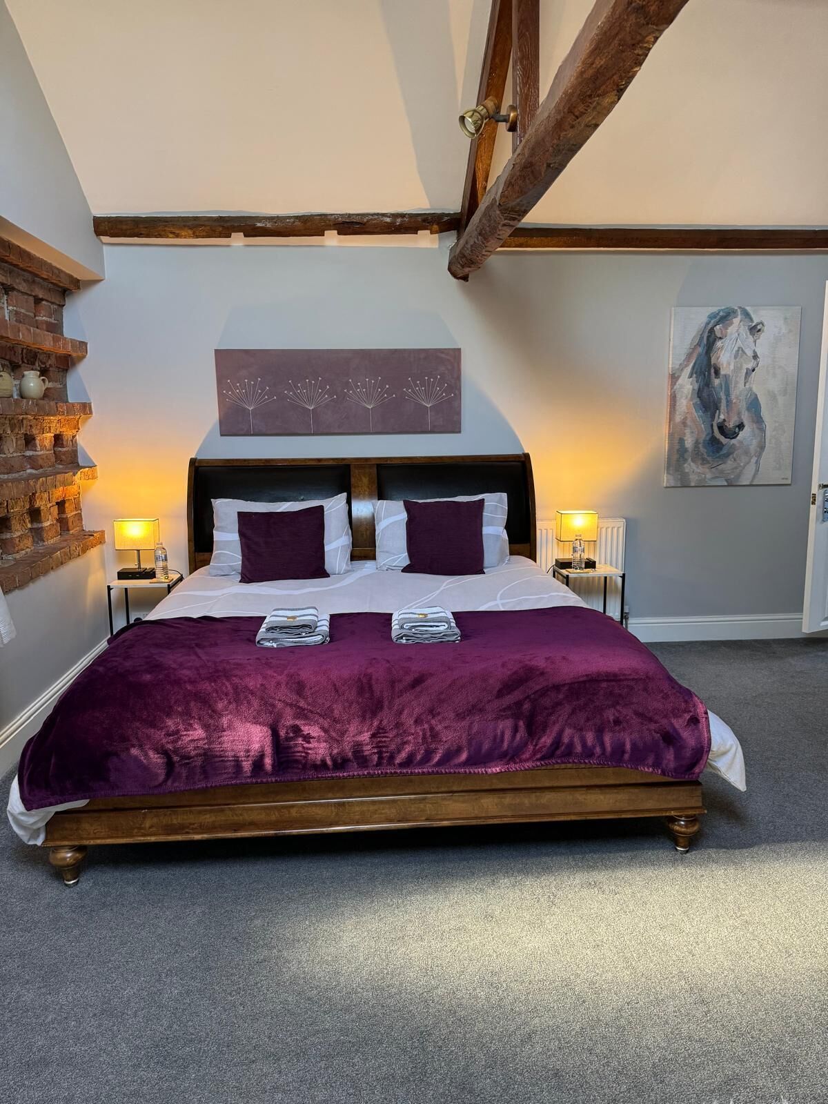Une chambre avec un grand lit, une tête de lit en bois et un mur en briques.