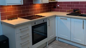 A modern kitchen with white cabinets, a built-in oven, and a gas stove.