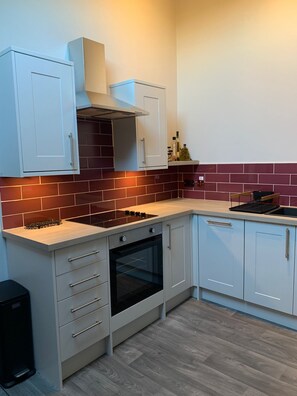 A modern kitchen with white cabinets, a built-in oven, and a gas stove. - The Carriage House, Bilbrough, York. (York)