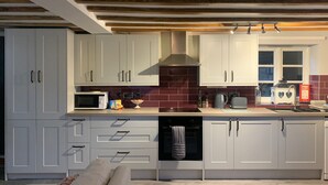 Une cuisine moderne avec des meubles blancs, un four à micro-ondes, une bouilloire et un grille-pain.