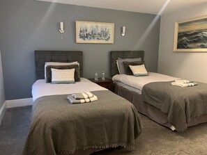 Habitación de hotel con dos camas, paredes grises y obras de arte sobre cada una.