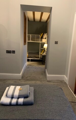 A narrow hallway leading to a room with a bunk bed, a lamp, and a carpeted floor. - The Carriage House, Bilbrough, York. (York)