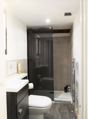 Un baño moderno con inodoro, lavamanos y ducha.