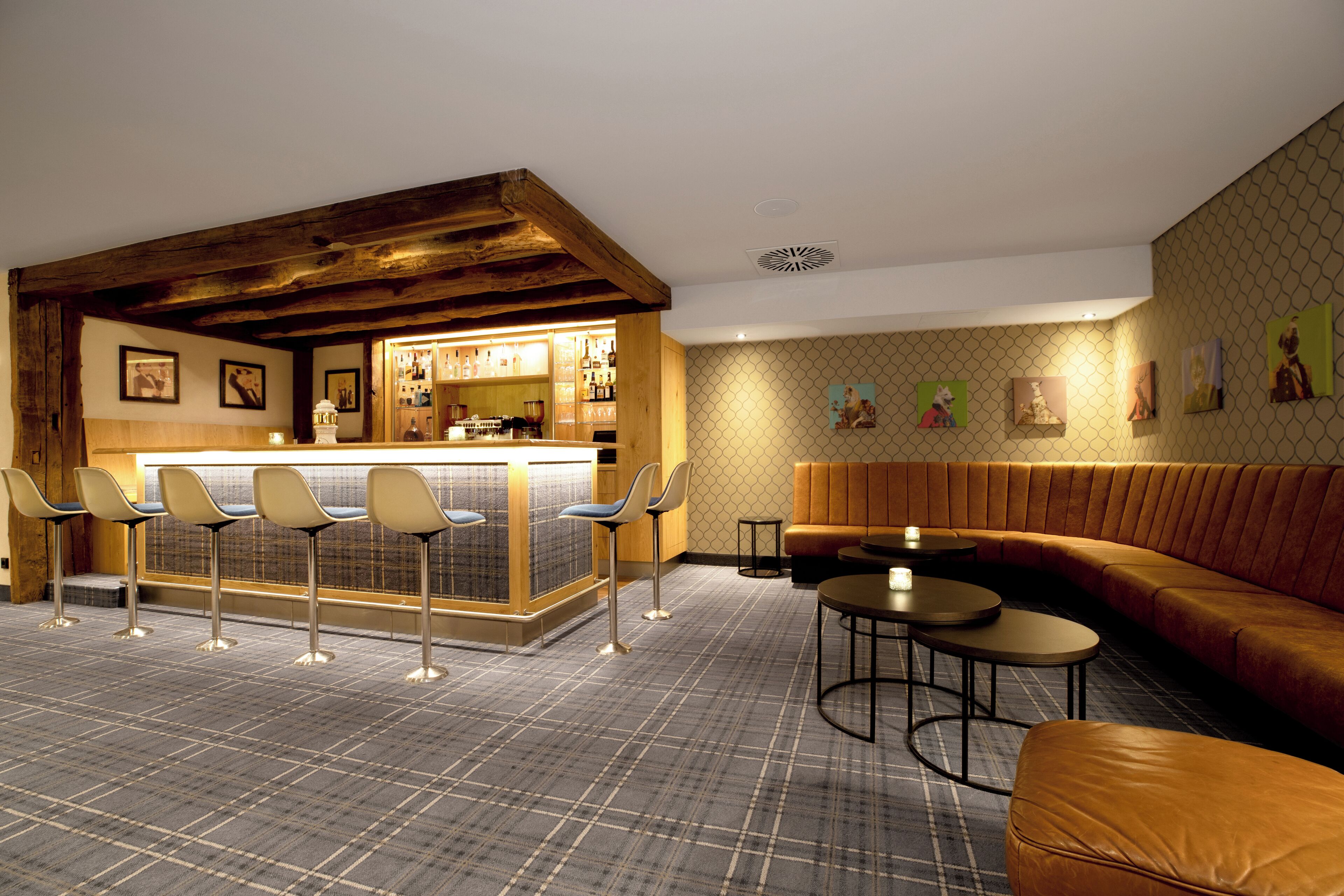 A bar area with stools, a bar counter, and a seating area with a sofa and tables.