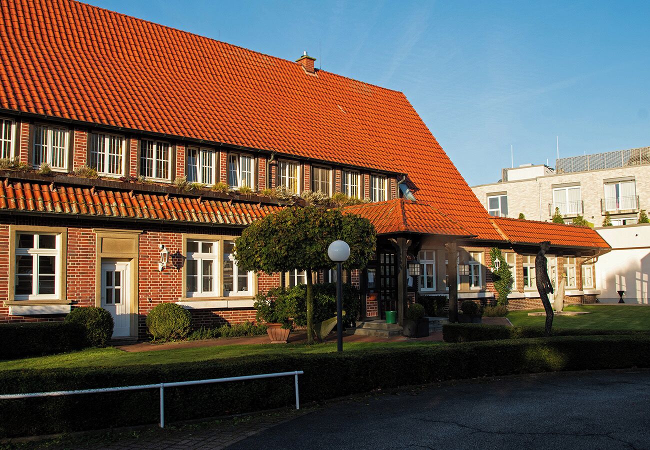 A building with a red-tiled roof, brick facade, and a covered outdoor seating area.
