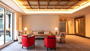 Eine Hotellobby mit Schachbrettmuster-Boden, einer Sofagarnitur und zwei roten Sesseln.