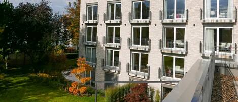A multi-story building with balconies, large windows, and a well-maintained garden.