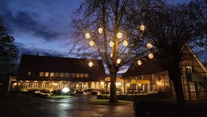 Un hôtel à la façade traditionnelle en briques, une entrée bien éclairée et un arbre décoré de guirlandes lumineuses.