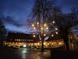 Um hotel com fachada de tijolos tradicionais, entrada bem iluminada e uma árvore decorada com luzes.