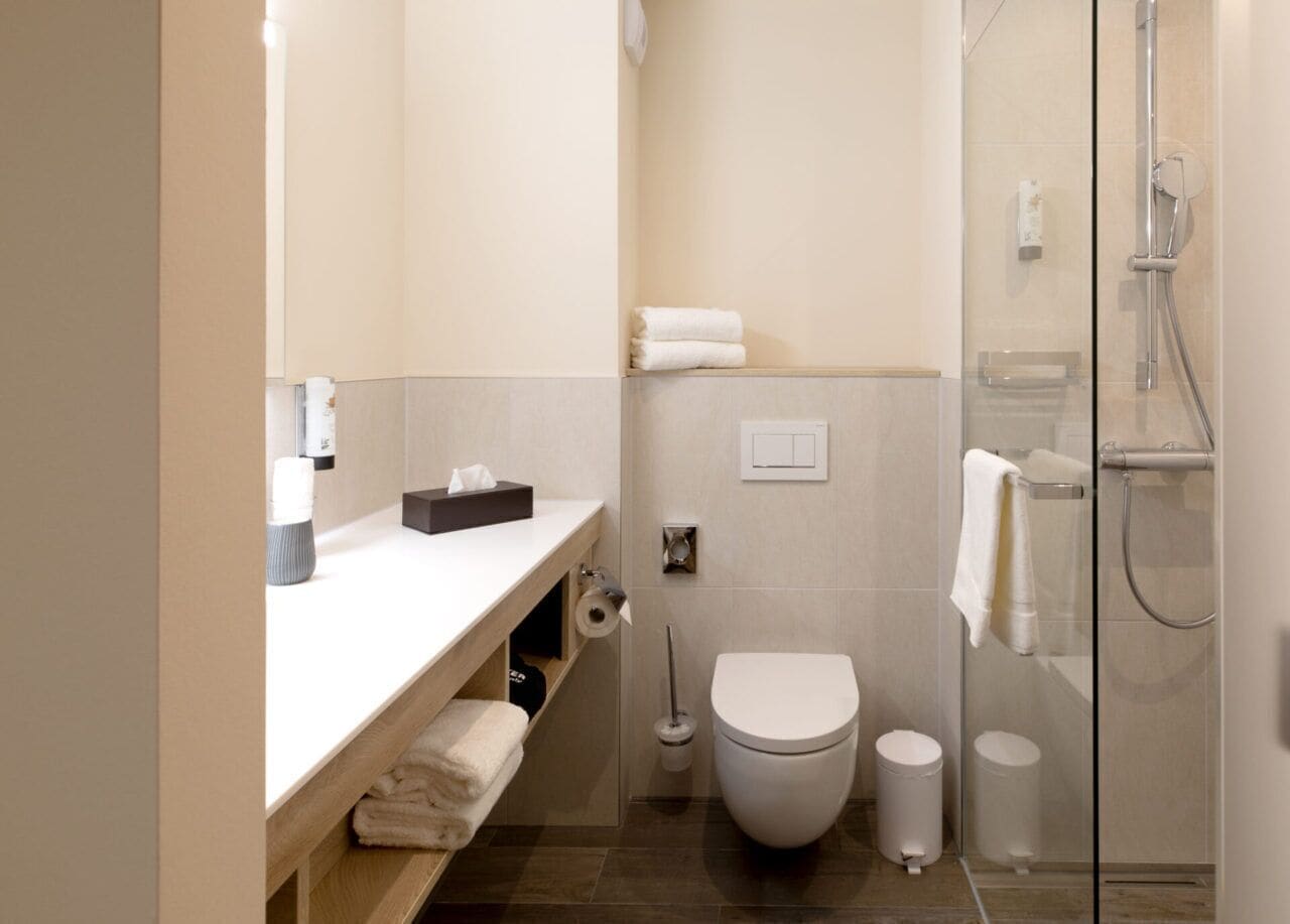 Une salle de bain moderne équipée de toilettes, d’un bidet et d’une douche à parois de verre.